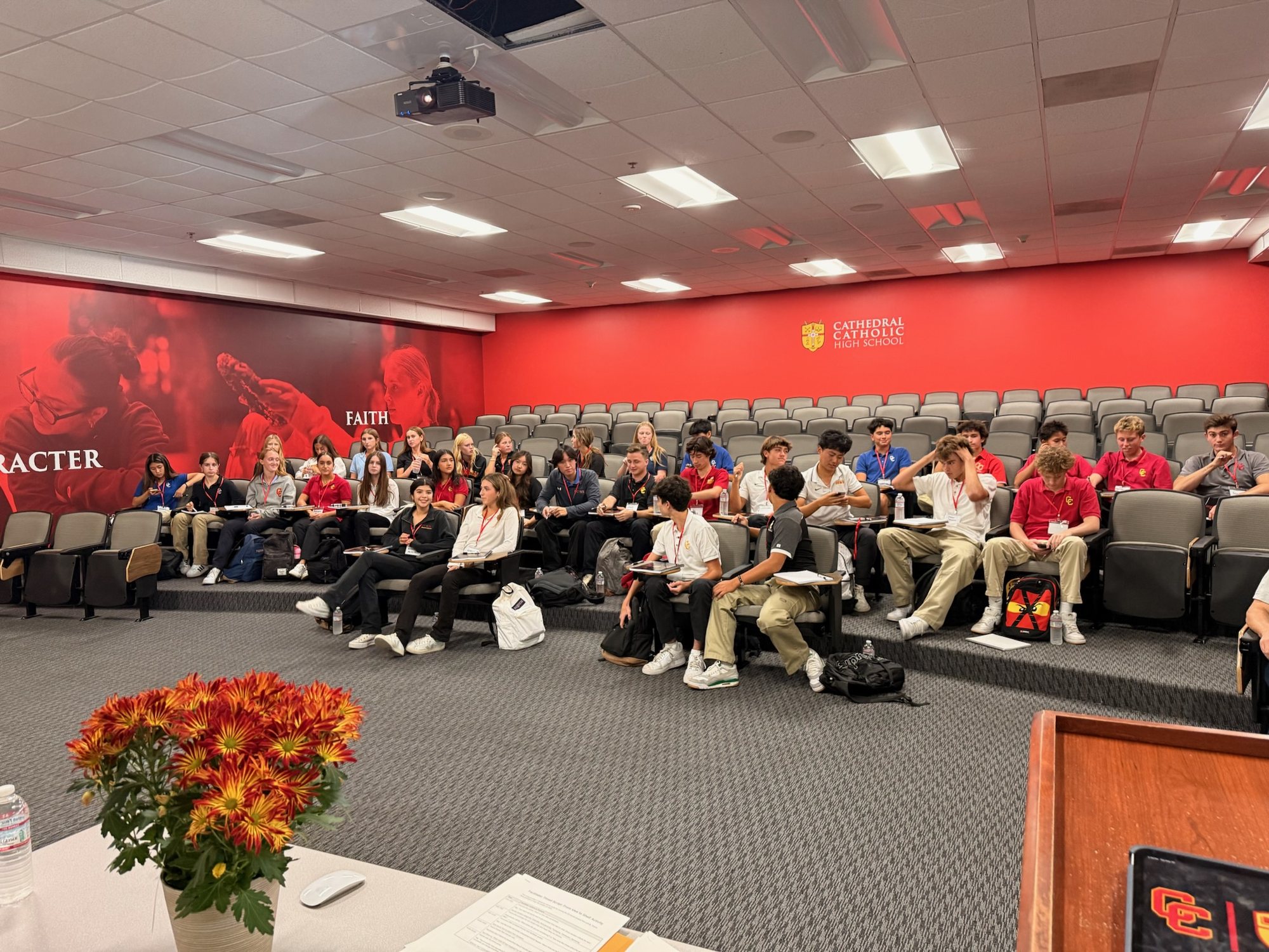 The DBI cohort seated in a Cathedral Catholic lecture hall beneath banners reading CHARACTER and FAITH.
