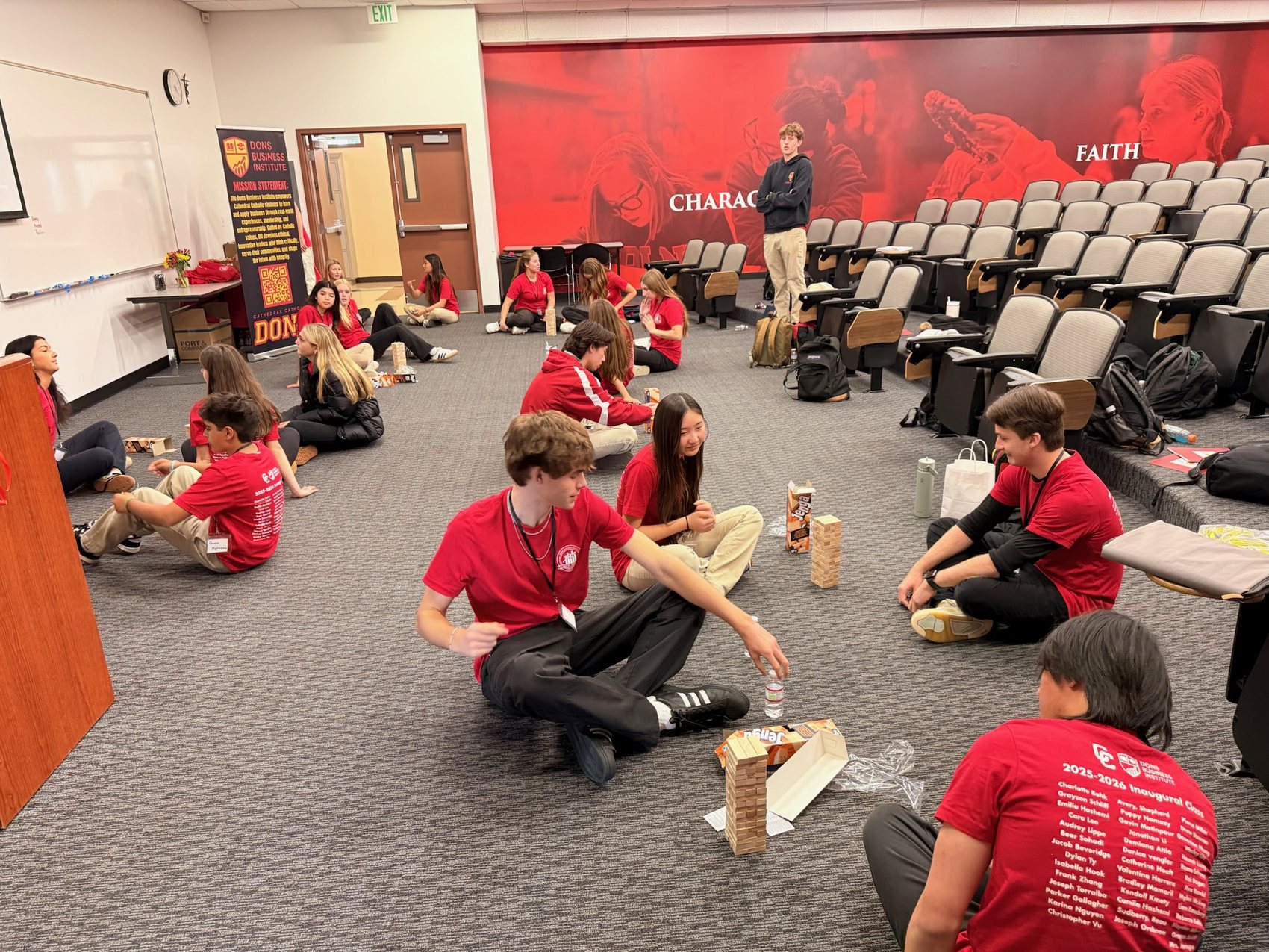 Students seated in a circle on the floor playing the Risk Game with wooden blocks.