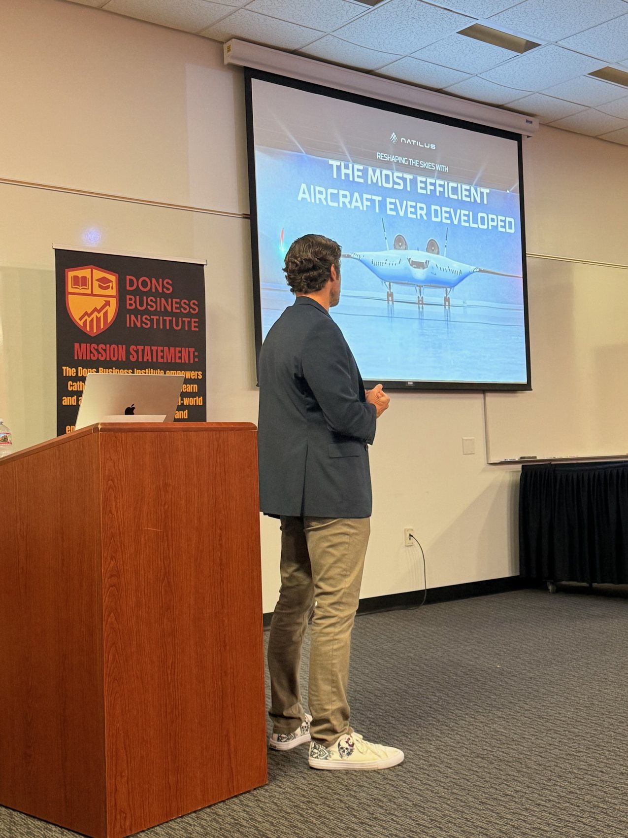 Justin Nahama presenting the Natilus pitch deck, a blended-wing aircraft on the screen.